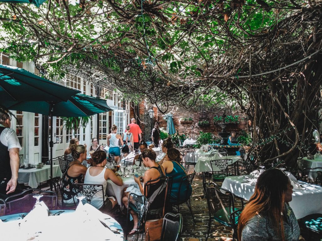 Courtyard dining at Court of the Two Sisters. Vine covered trees and wrought iron chairs.