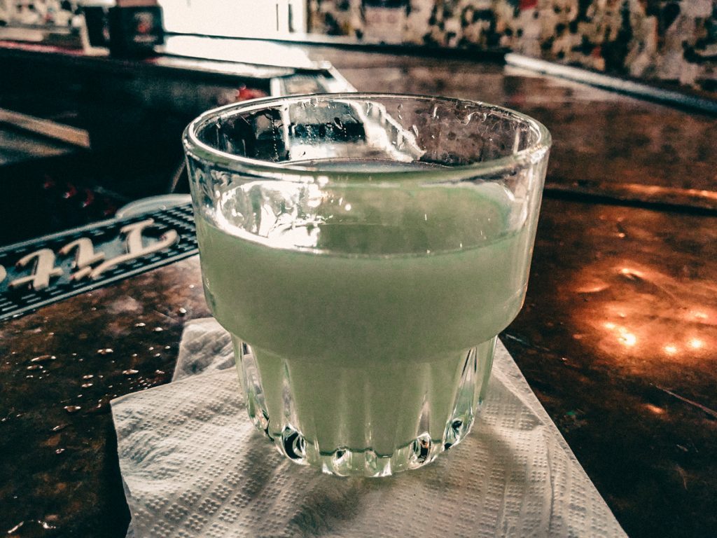 Glass of milky absinthe on top of an old bar.