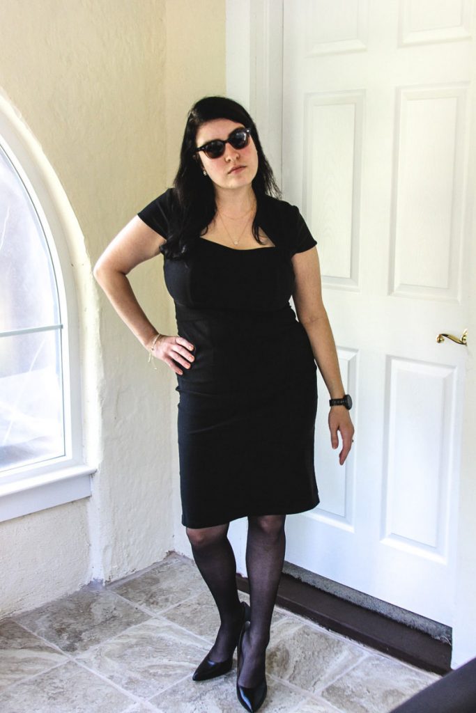 Little black cocktail dress, pale skin, alternative woman, sunglasses, doorway, black high heeled shoes